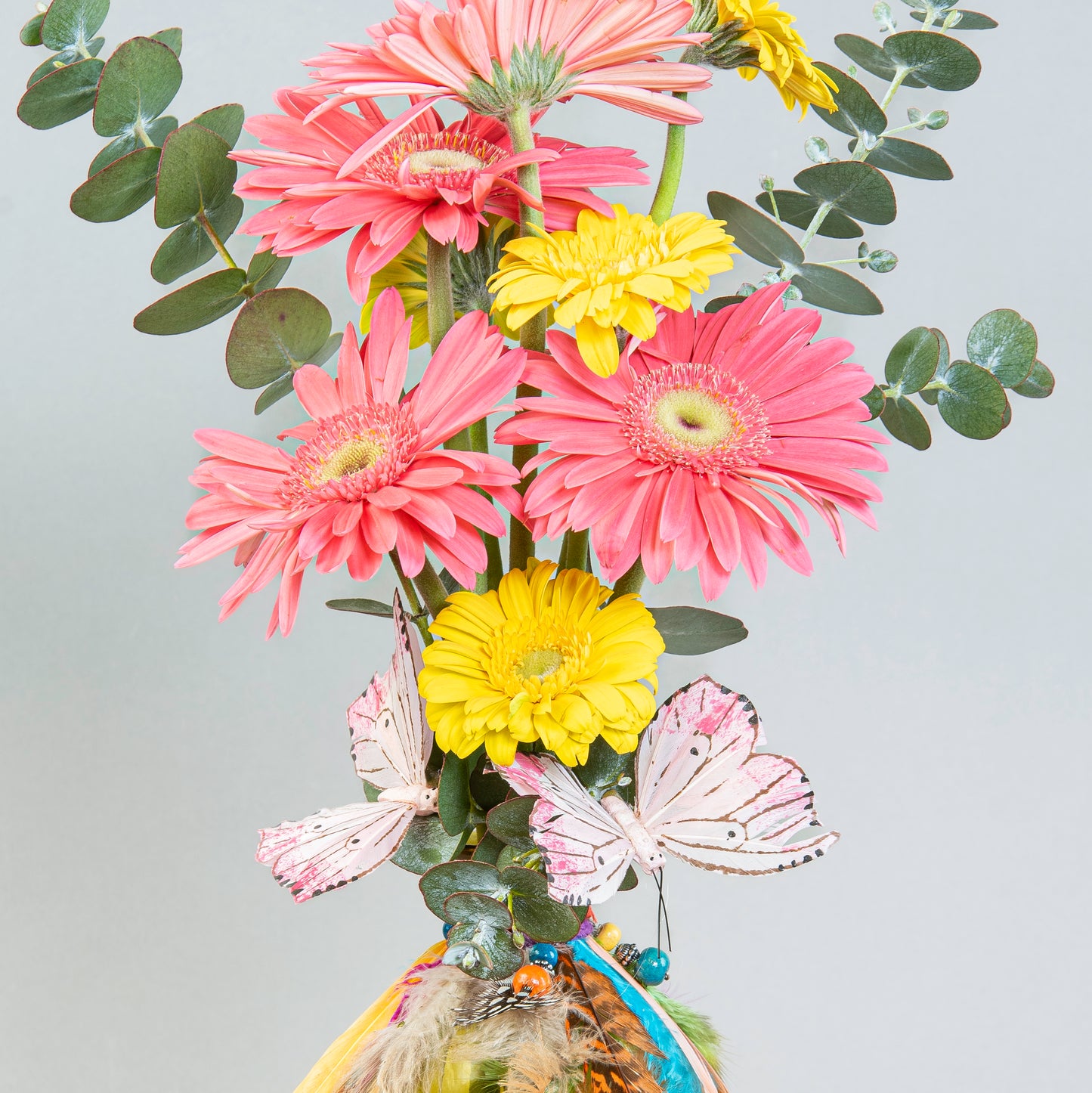 Sunshine Whimsy: Pink and Yellow Gerberas in Yellow Bottle with Feathers